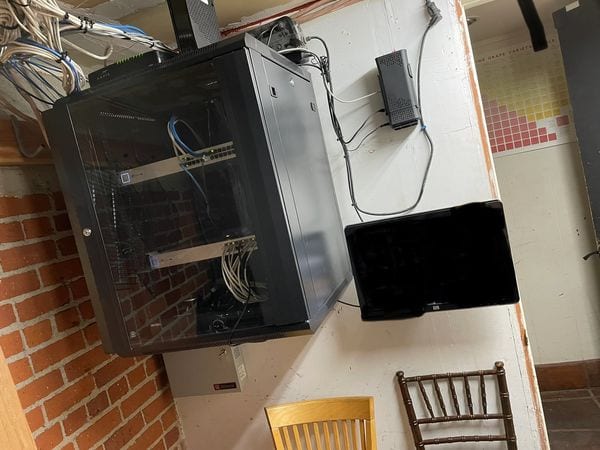An enclosed wall-mounted network cabinet installed on a finished wall with cabling dressed and run out of sight